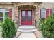 Elegant double front doors with glass inserts and red finish, framed by stone and manicured greenery at 332 Warwick Pl, Mcdonough, GA 30253