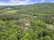 This aerial view captures a secluded home nestled in dense greenery with a pool surrounded by picturesque mountain views at 3630 Spot Rd, Cumming, GA 30040