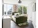 Bright bedroom with an exposed brick wall, large windows, and a comfortable green upholstered bed at 800 Peachtree Ne St # 8531, Atlanta, GA 30308
