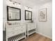 Bright bathroom featuring double sinks with white cabinets, modern fixtures, and wood flooring at 2148 Allgood Rd, Marietta, GA 30062