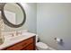 Neat powder room featuring a wood vanity and a round decorative mirror at 815 Spring View Ct, Covington, GA 30014