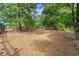 View of a wooded backyard area with trees and leaf-covered ground with partial fencing at 75 Auburn Rd, Auburn, GA 30011