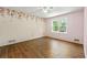 Bright bedroom with light pink walls, wood floors, ceiling fan, and a large window at 385 Russell Ridge Dr, Lawrenceville, GA 30043