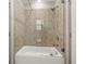 A clean bathroom featuring tile walls, a shower head, and a white bathtub with glass shower door at 4015 Roberts Crest Ln, Suwanee, GA 30024