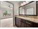 Bathroom vanity with granite countertops, dark cabinets, and large mirror is open to the bedroom beyond at 4015 Roberts Crest Ln, Suwanee, GA 30024
