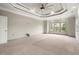Bedroom showcases a tray ceiling, neutral paint and carpet, and exterior views at 4015 Roberts Crest Ln, Suwanee, GA 30024