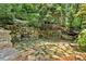 Secluded patio features stone walls and flagstone pavers surrounded by lush, mature landscaping at 400 Old Ivy Ne Rd, Atlanta, GA 30342