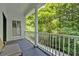 Covered porch features a gray floor, bench seating, and a white railing overlooking a lush, wooded landscape at 400 Old Ivy Ne Rd, Atlanta, GA 30342