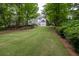 Spacious backyard with a gentle slope, mature trees, and a view of the home's rear exterior at 5844 Brookstone Nw Walk, Acworth, GA 30101