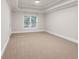 Bright, carpeted bedroom featuring a tray ceiling, crown molding and a window with privacy blinds at 5844 Brookstone Nw Walk, Acworth, GA 30101