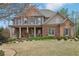 Charming two-story home with a brick and stone facade, covered porch, manicured lawn, and professional landscaping at 1870 Marcia Overlook Dr, Cumming, GA 30041