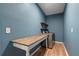 Spacious laundry room with blue walls, wooden floor, wooden shelf and table, and a modern washer and dryer at 2772 Hillgrove Dr, Dacula, GA 30019