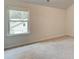 An empty bedroom featuring a neutral carpet, white walls, and a window overlooking the property at 165 Cooper E Cv, Fayetteville, GA 30215