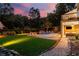 Backyard view showcasing the pool, grilling area, and outdoor patio illuminated at dusk at 360 Spindle Ct, Sandy Springs, GA 30350