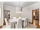 Bright dining room with white table and chairs with modern light fixture, open to kitchen and hallway at 360 Spindle Ct, Sandy Springs, GA 30350