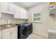 Functional laundry room with modern washer and dryer, white cabinetry, and a sink for added convenience at 360 Spindle Ct, Sandy Springs, GA 30350