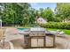 View of the stainless steel outdoor kitchen and the pool, nestled in a private backyard with mature trees at 360 Spindle Ct, Sandy Springs, GA 30350