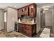 Basement wet bar with granite countertop, dark cabinets, wine cooler, and modern backsplash, next to a doorway at 360 Spindle Ct, Sandy Springs, GA 30350