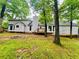 A home's backyard featuring lush green grass, mature trees, a wooden deck, and vinyl siding at 1905 Sidneys Cv, Lawrenceville, GA 30043
