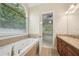 Bathroom featuring soaking tub, arched window, and a view into the main bedroom at 223 Falling Water Way, Woodstock, GA 30188