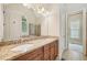 Bathroom featuring dual sinks, granite countertop, wood cabinets, large mirror, arched window, and tub-shower combo at 223 Falling Water Way, Woodstock, GA 30188