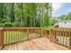 A wooden back deck with a wooden safety rail overlooks the green grass and tree-lined backyard at 1137 Poplar Log Pl, Austell, GA 30168