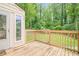 View of a wooden back deck with a wooden safety rail overlooking a green tree-lined backyard at 1137 Poplar Log Pl, Austell, GA 30168