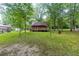 Exterior shot of a wooded cabin showcasing its lovely backyard, trees, and spacious wooden deck at 218 Green Acre Ln, Cartersville, GA 30121
