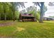 A well-maintained log cabin with a covered porch, nestled among mature trees on a grassy lot at 218 Green Acre Ln, Cartersville, GA 30121