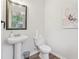 A half bathroom featuring a pedestal sink, toilet, and a modern mirror and light fixture at 236 Arbor Creek Dr, Dallas, GA 30157