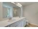 Bathroom with double sink vanity with white cabinets, large mirror, and wood-look flooring at 389 Navigator Ln, Mcdonough, GA 30253