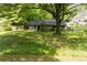 View of a large backyard with a small block building and a house in the background surrounded by trees at 1395 Clay Sw Rd, Mableton, GA 30126
