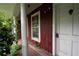 Close-up of front porch with white door and aged brickwork, enveloped by lush greenery at 1395 Clay Sw Rd, Mableton, GA 30126
