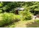 Small, overgrown shed in a lush green yard with a chain link fence adding a touch of rustic charm at 1395 Clay Sw Rd, Mableton, GA 30126