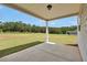 Covered back porch with concrete floor, white support columns and backyard meadow at 715 Colvin Dr, Locust Grove, GA 30248