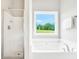 Bright bathroom with a soaking tub under a window and a glass enclosed shower at 715 Colvin Dr, Locust Grove, GA 30248