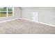A carpeted room has a large window and a white door at 715 Colvin Dr, Locust Grove, GA 30248