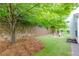 Spacious backyard featuring a small grass yard with a retaining wall, tree, and patio set at 118 Brendylynn Trce, Woodstock, GA 30188