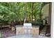 Stone outdoor kitchen with stainless steel grill set amongst mature trees at 760 River Gate Dr, Atlanta, GA 30350