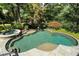 An eye-level view of a luxurious kidney-shaped pool and spa surrounded by lush greenery at 760 River Gate Dr, Atlanta, GA 30350