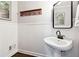 Elegant powder room featuring white wainscoting, pedestal sink, and a classic wood-framed mirror and accent shelf at 151 Overhill Point, Alpharetta, GA 30005