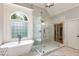 Elegant bathroom featuring a soaking tub, glass-enclosed shower, and a large window with decorative glass at 5173 Brendlynn Dr, Suwanee, GA 30024