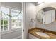 Bright bathroom with granite countertop vanity, round mirror, shiplap wall, and natural light at 5173 Brendlynn Dr, Suwanee, GA 30024