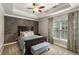 Relaxing bedroom with natural light, tray ceiling, and decorative wood accent wall at 5173 Brendlynn Dr, Suwanee, GA 30024