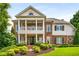 Stately brick home with a columned front porch, balcony, manicured lawn, and mature landscaping at 5173 Brendlynn Dr, Suwanee, GA 30024
