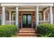 Elegant brick home with a grand entrance featuring double doors, white columns, and meticulously manicured landscaping at 5173 Brendlynn Dr, Suwanee, GA 30024