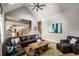 Open-concept living room with vaulted ceilings, a ceiling fan, a leather sectional, and access to the kitchen at 5173 Brendlynn Dr, Suwanee, GA 30024
