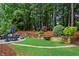 Lush backyard featuring a stone walkway and manicured greenery, enhanced by a multi-tiered retaining wall and beautiful plants at 107 W Point Trl, Woodstock, GA 30189