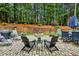Spacious backyard featuring a paved patio with fire pit, seating, and a wooded backdrop at 107 W Point Trl, Woodstock, GA 30189