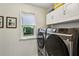 Modern laundry room with stainless steel washer and dryer, storage cabinets, and a window at 107 W Point Trl, Woodstock, GA 30189